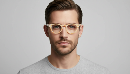 Man wearing gold-rimmed glasses against a gray background