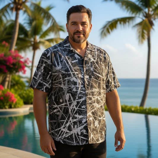 Man wearing a patterned shirt standing by a pool with palm trees and flowers in the background