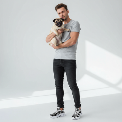 Man holding a pug in a studio setting with a white background